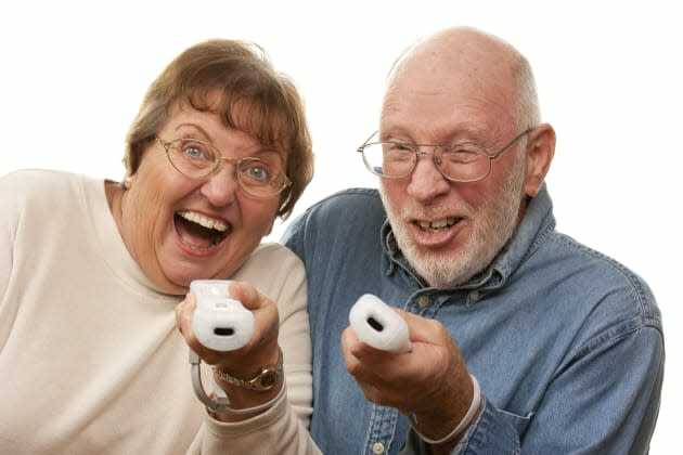 Šťastný starší pár hrát videohru s dálkovými ovladači